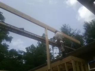 Carpenter setting a ridge beam over a new addition frame — Ice Dam Removal by Roofing Brothers in Matherville