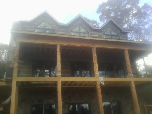 Dormers and porch framing on a large log home under construction — Roof Coating work by our crew in Matherville