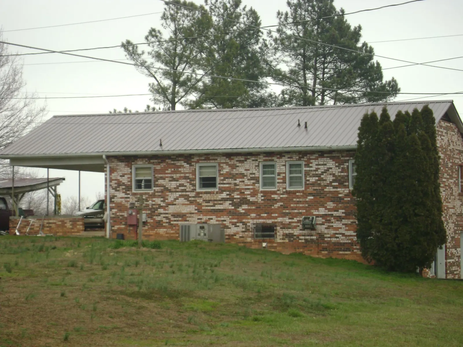 Gray metal roof on a brick split level home with a carport in Matherville