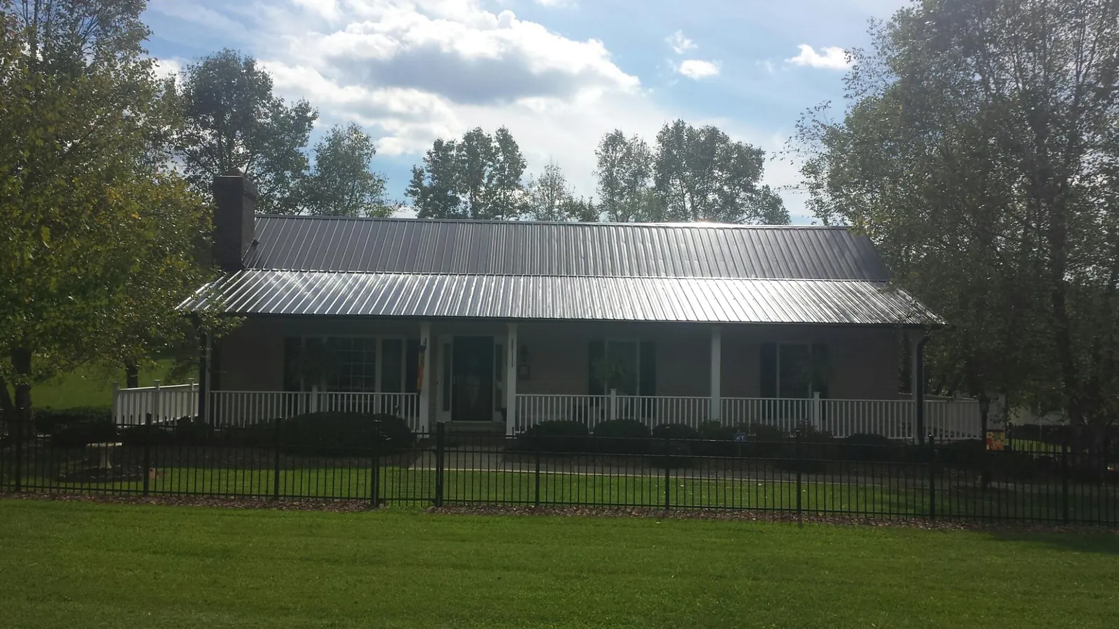Gray metal roof on a brick ranch with a full width front porch — Gutter Guard Installation work by our crew in Matherville