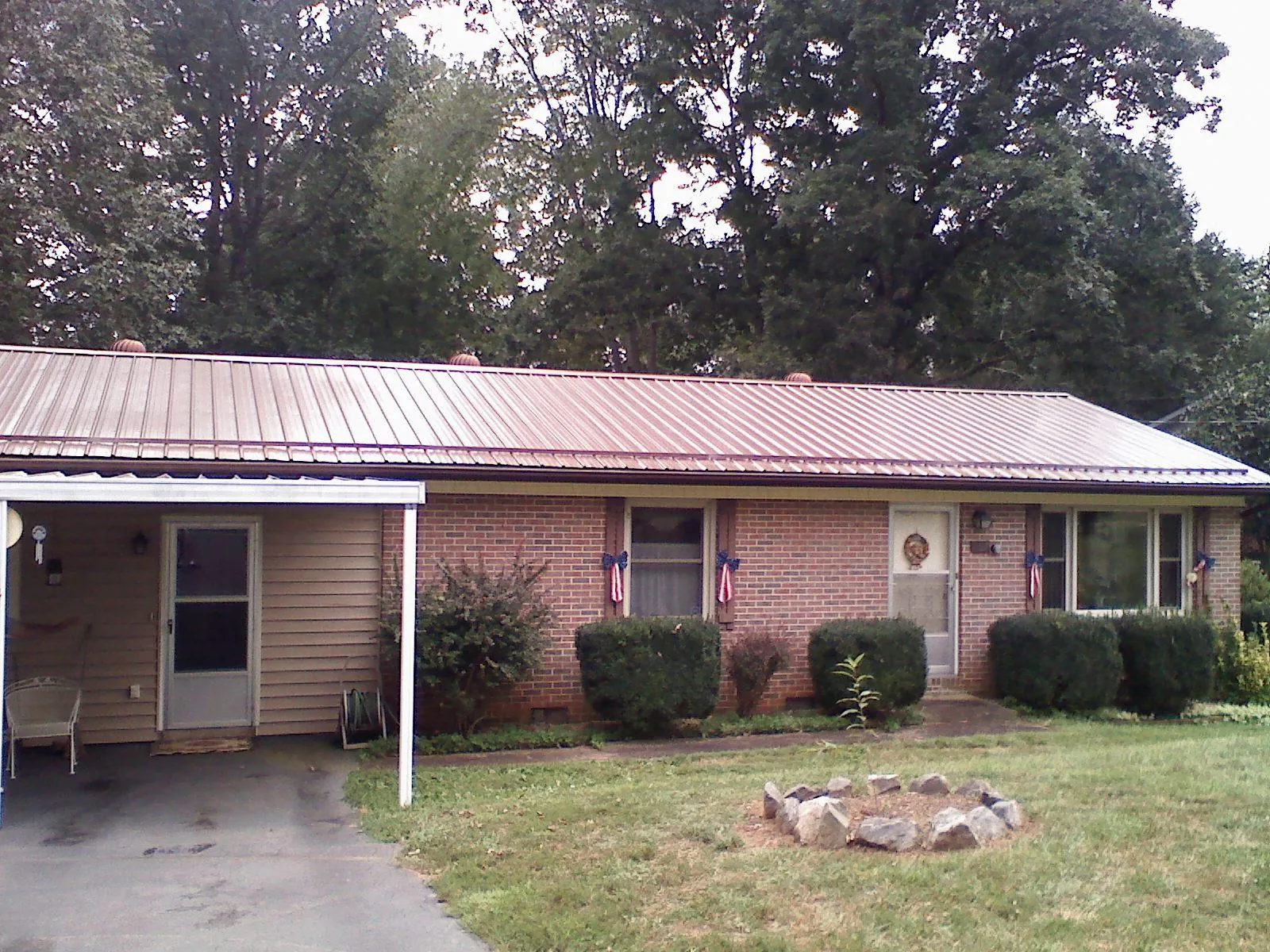 Bronze metal roof and carport on a brick ranch home — Roof Repair work by our crew in Matherville