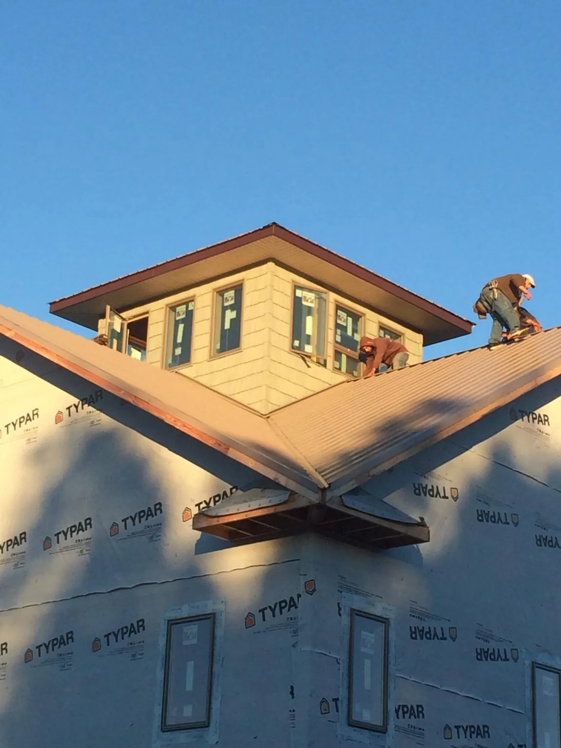 Roofers working around a rooftop cupola on a new metal roof at sunset — Roof Waterproofing in Matherville by Roofing Brothers